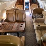 Bombardier Challenger CL604 aircraft interior cabin with beige seating and table