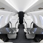 The Best Personal Aircraft: Interior of Pilatus PC-24 aircraft cabin with white and black seats and pull out tables