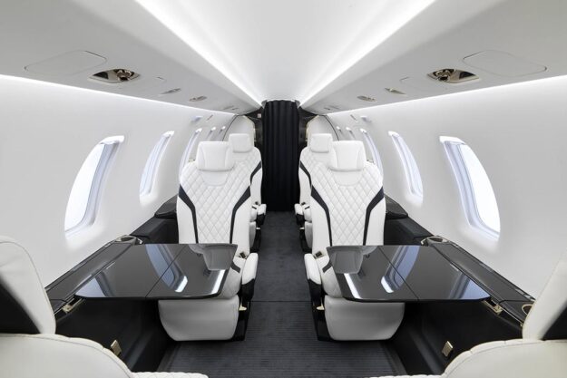 The Best Personal Aircraft: Interior of Pilatus PC-24 aircraft cabin with white and black seats and pull out tables