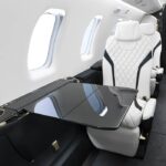 Interior of Pilatus PC-24 aircraft cabin with white and black seat and table